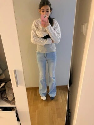 Ljusblå bootcut jeans - Snygga ljusblå bootcut jeans med klassisk femficksmodell och lätt slitning framtill. Jeansen har hög midja och utsvängda ben, perfekta för en trendig och avslappnad look. Materialet är mjukt denim som ger en bekväm känsla hela dagen.