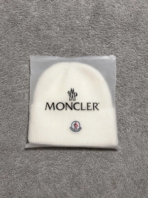 Moncler Unisex Mössa (VIT) - One size moncler. Gjord av ull inte använd. Kommer med allt men ser på bilden.                      Mer info för köpare.