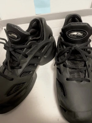 Svarta Adidas Climacool sneakers/ Yeezys dupe - Svarta Adidas Climacool sneakers med futuristisk design och ventilerande meshpaneler. Skorna har svarta snören, robust sula och coola detaljer i plast och mesh för extra andningsförmåga. Perfekta för dig som gillar sportig och unik stil.