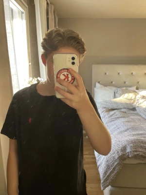 Svart t-shirt från Polo Ralph Lauren - Klassisk svart t-shirt från Polo Ralph Lauren med röd broderad logga på bröstet. T-shirten har rund halsringning och korta ärmar. Tillverkad i mjuk bomull för skön känsla och enkel stil.