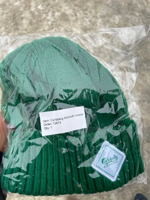 Grön Carlsberg mössa limited edition  - Säljer en snygg tvåfärgad grön mössa från Carlsberg med patch framtill där det står 'Carlsberg Alcohol Free'. Mössan är ribbstickad och har en uppvikt kant. Perfekt för dig som vill ha en unik accessoar med streetkänsla.