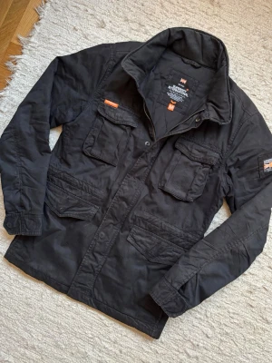 SUPERDRY FIELDJACKET - En mycket trevlig fieldjacket från det omtyckta märket Superdry! Passar perfekt nu när våren nalkas. Storlek M, hör av dig vid frågor!