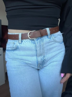 Brunt stilrent skärp från H&M, storlek M - Snyggt brunt skärp med guldfärgat spänne. Stilrent, knappt använt. Nyskick.