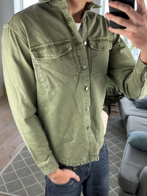 Olivgrön overshirt/jeansjacka - Mycket trendig och stilren perfekt att kombinera med hoodie under! Mått: A:50 B:48 C:48 D:62 (cm) Skriv vid fundering 😇🙌