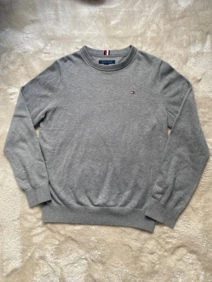 Grå stickad tröja från Tommy Hilfiger - Snygg grå tröja från Tommy Hilfiger i nyskick, endast använd någon enstaka gång. Riktigt stilren och passar till allt. Postar inom 24h📦 Köp mer än ett plagg för 10% rabatt🤝 Tveka inte på att höra av er vid frågor eller funderingar!