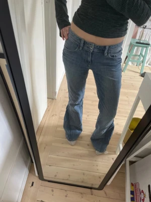 Utsvängda jeans - Jag säljer ett par blå utsvängda midwaist jeans med fin tvätt och coola bakfickor. Jeansen har på sytt jeans tyg på längderna så att dem är utsvängda.