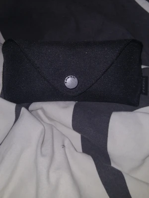 Transparenta solglasögon från Everest - Snygga solglasögon från Everest med transparent båge och mörka glas. Medföljer ett svart fodral i tyg med knappstängning. Perfekta för soliga dagar och ger en cool vibe till din outfit.