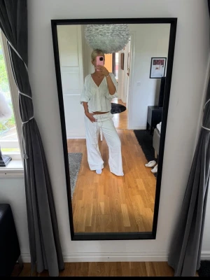 Vita vida byxor med dragsko - Säljer ett par vita byxor med avslappnad passform och dragsko i midjan. Byxorna har raka ben och är tillverkade i ett lätt och luftigt linnematerial, perfekta för en chill och stilren look. Byxorna är i nytt skick med prislappar kvar! Nypris 300 kr🤍