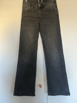 Gråa bootcut jeans med fem fickor - Säljer ett par gråa bootcut jeans med klassisk femficksdesign och knappgylf. Jeansen har en lätt utsvängd passform nedtill och är tillverkade i denim. Perfekta för dig som gillar en avslappnad men ändå trendig look. Från lager 157. Storlek XS