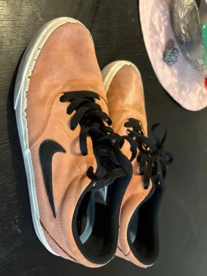 Nike SB rosa sneakers mocka - Säljer ett par Nike SB sneakers i rosa mocka med svart swoosh och svarta skosnören. Skorna har vit sula och svart innerfoder. Klassisk låg modell som passar perfekt till streetwear och skate. Materialet är mjuk mocka och designen är stilren med tydliga Nike-detaljer. Säljs bara second hand finns inte att köpa hört nya längre i gott skick 