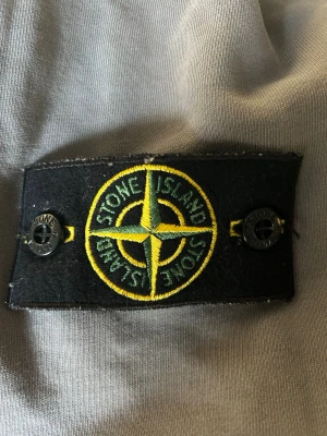 Grå sweatshirt från Stone Island - Säljer en grå sweatshirt från Stone Island med den klassiska loggan på vänster arm. Tröjan har knappt används och är köpt för 2300. Perfekt för en stilren outfit. Pris kan självklart diskuteras vid snabb affär och tveka ej att skriva till mig vid några frågor🙌🙌