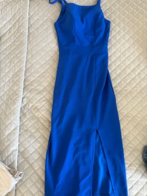 Blå långklänning med slits - Snygg blå långklänning med smala axelband och en stilren, figurnära passform. Klänningen har en slits framtill som ger en trendig touch. Perfekt för dig som vill sticka ut med en klar färg och enkel design. Perfekt nu till lite varmare väder💕💕💕 ( orginalpris 699kr) 