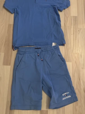 Shorts och piketröja set - Ett set med ett par blå shorts och en blå piketröja från Tommy Hilfigger. De är köpta tillsammans men kan säljas separat.  Tröjarn är 176 och shortsen 164