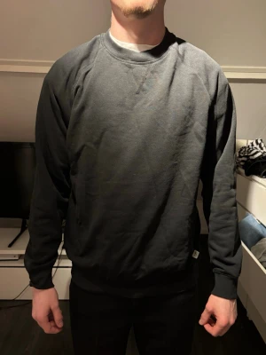 Svart sweatshirt med rund hals - En enkel svart sweatshirt med rund halsringning och långa ärmar. Tröjan har ribbade muddar vid ärmslut och nederkant. Perfekt för en avslappnad och stilren look. Tillverkad i mjukt material för extra komfort.