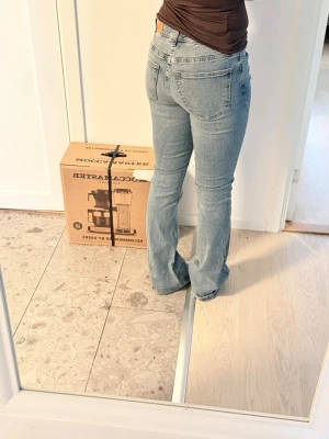 Ljusblå bootcut jeans - Säljer ett par ljusblå bootcut jeans med klassisk femficksmodell och normal midja. Jeansen har en avslappnad passform över låren och lätt utsvängda ben. Perfekta till vardagslooken och tillverkade i mjuk denim för skön känsla.
