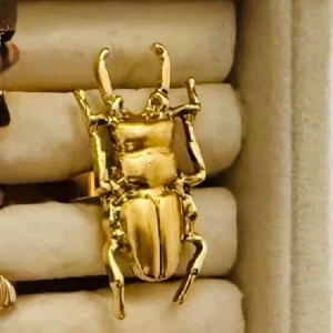 Guldfärgad skalbagge ring  - Unik brosch i form av en skalbagge i blank guldfärg. Broschen har detaljerade ben och antenner som ger ett coolt och edgy intryck. Perfekt accessoar för dig som vill sticka ut och addera en statement piece till din outfit.