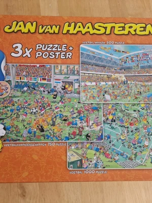 Jan van Haasteren fotbollspussel 3-pack - Säljer ett set med tre kompletta och färgglada pussel från Jan van Haasteren med fotbollstema. Paketet innehåller 500, 750 och 1000 bitars pussel samt en poster. Motiven är tecknade och fulla av roliga detaljer från fotbollsmatcher och publik.