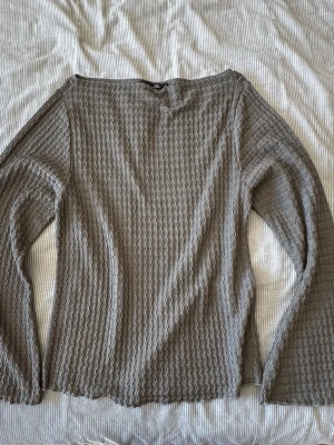 Grön våfflad långärmad tröja 157 - Säljer en grön långärmad tröja från 157 med våfflat, vågigt mönster i tyget. Tröjan har en rak passform och rak halsringning. 