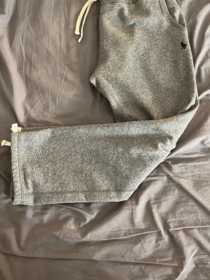 Polo Ralph Lauren mjukisbyxor - Snygga grå mjukisbyxor från Polo Ralph Lauren med klassisk logga broderad på benet. Byxorna har dragsko i midjan och raka ben. Tillverkade i mjukt och bekvämt material, perfekta för chill dagar hemma eller när du vill vara extra comfy.