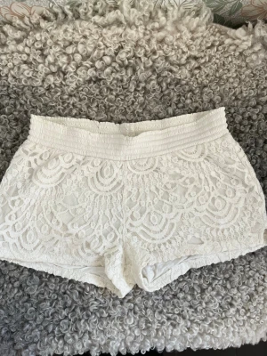 Vita spets-shorts med low waist! - Säljer ett par vita shorts med Låg midja och bred resår. Shortsen har ett detaljerat spetsmönster över hela och är fodrade. Dessa shorts är storlek 146-156 men passar mig som är XS.🤗🤗
