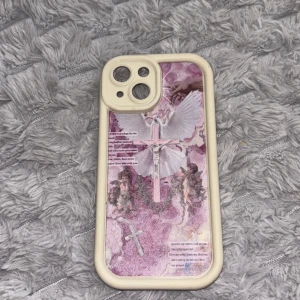 Beige mobilskal iphone 15  - Snyggt mobilskal i beige med lila och vitt motiv av en ängel och kors på baksidan. Skalet har en mjuk, tålig ram och passar till en mobil med dubbla kameror. Perfekt för dig som vill ha ett unikt och konstnärligt skal till din telefon.