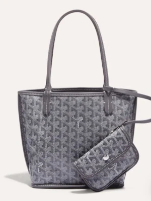 Intressekoll - Snygg grå tote-väska med klassiskt mönster och matchande clutch. Väskan har två långa handtag och är tillverkad i ett glansigt material med tryckt logotyp. Perfekt för dig som vill ha plats för allt och ändå se trendig ut. Inte använd mycket. Kollar bara intresse så tryck inte på köp nu