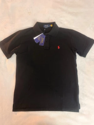 Svart Polo Ralph Lauren Piké  - Aldrig använd med prislapp kvar. Storlek M och pris kan diskuteras