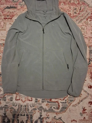 Nike Unlimited Tracksuit - Inga fel på själva tracksuiten bara att på jackan så finns det 2 hål, En pyttelitet vid loggan, Och en lite större på baksidan av jackan, Plastgrejen på snören på byxorna ramlade också.