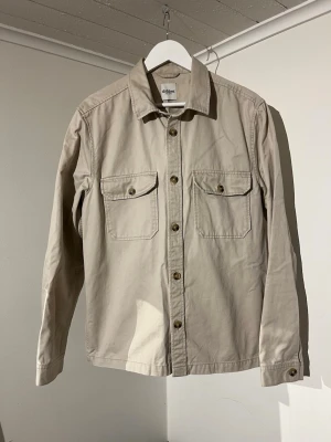 Beige Dobber Overshirt  - Säljer denna sjukt snygga Overshirten från Dobber⭐️ Färgen är beige och storleken är M✅ Den har inga defekter och skicket är utomordentligt🙌🤝 Sjukt najs passform och passar perfekt till hösten☀️🙌 Tveka inte på att höra av er dig vid minsta fråga eller fundering😊