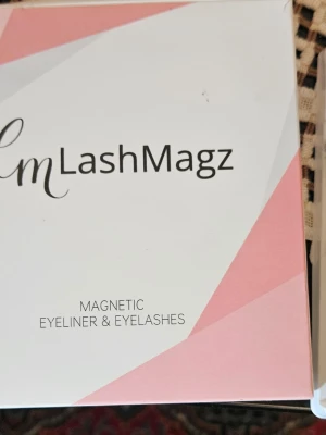LashMagz magnetiska fransar & eyeliner - Magnetiska lösögonfransar och eyeliner från LashMagz. Förpackningen är vit och rosa med stilren design. Fransarna är svarta och fylliga, och eyelinern används för att fästa fransarna enkelt med magneter. Perfekt för dig som vill ha en smidig lösning för snygga ögon.