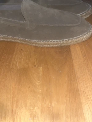 Bruna mockaloafers med flätad sula - Säljer ett par stilrena loafers i brun mocka med grov, flätad sula. Skorna har en klassisk slip-on design och är perfekta för dig som gillar en avslappnad men ändå snygg look. Materialet är mjukt och ger en skön känsla på foten. Storlek 44 och i helt nyskick