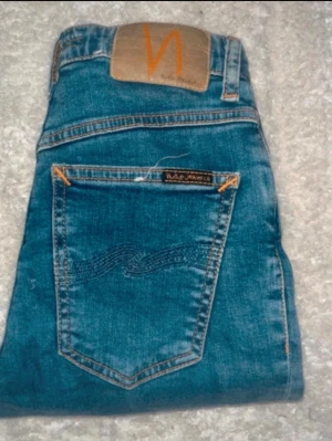 Nudie jeans  - Blåa skinny jeans från Nuie Jeans. Midja 28cm, längd 93cm. Obs jeansens benslut är avklippta, så kolla måtten. JAG SKICKAR EJ FLER BILDER NÄR JAG BÄR JEANSEN! för bättre inblick i passformen rekommenderar jag att googla på modellnamnet. För storleksguide kolla måtten noggrant då jeansen alltid kan vara uppsydda heller krympta och jag ej tar emot returer :) s6,4