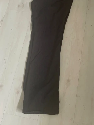 Dressman Svarta kostymbyxor med diskreta ränder - Säljer ett par svarta kostymbyxor från Dressman  med subtila vertikala ränder. Byxorna har rak passform och klassisk midja. Perfekta för en clean och stilren look. Materialet ser ut att vara en blandning av polyester och viskos för en mjuk känsla. Storlek 33.32