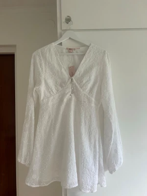 Vit broderad kortklänning med v-ringning - Söt klänning som jag köpte till min konfirmation, men den kom aldrig till användo 🩷 den har lappen kvar