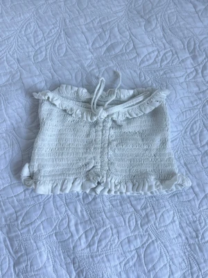 Vit smockad bandeau topp  - Använt endast ett fåtal gånger! En vit bandeau topp med smockad struktur, samt knytband framtill. Den ser mycket mindre än vad den är. 
