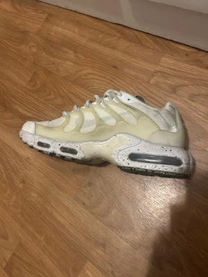 Nike Air Max  - Nike Air Max Plus sneakers i vitt med mesh och syntetiska detaljer. Skorna har den ikoniska vågiga designen på ovandelen och synliga Air-enheter i sulan för extra komfort. Snygg och sportig look med vita och ljusgrå toner samt prickig mellansula.