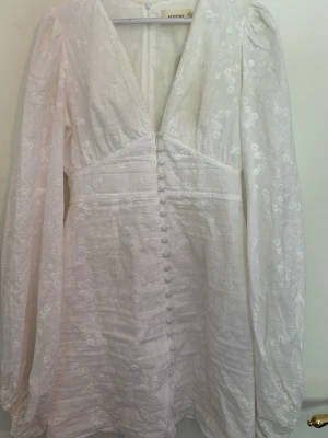 Vit ”FLORENCE DRESS” från Adoore - Säljer denna superfina och populära vit klänning ”FLORENCE DRESS” från Adoore med broderade blommor, djup v-ringning och långa puffärmar. Klänningen har använts en gång men har fortfarande prislappen på. 