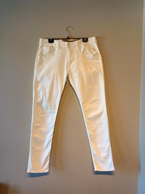 Vita anbass jeans från Replay - Säljer ett par vita skinny jeans från Replay med klassisk femficksdesign och dragkedjegylf. Jeansen är i stretchigt denimtyg som sitter snyggt och bekvämt. Perfekta för dig som vill ha en clean och fräsch look.