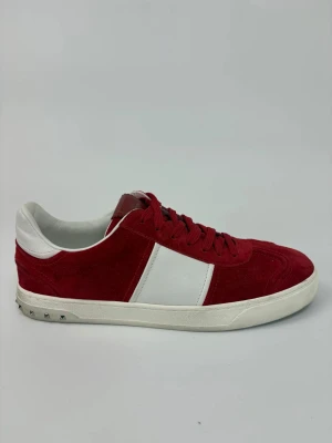 Valentino flycrew skor - Snygga sneakers från Valentino i rött mocka med vita detaljer och snörning. Skorna har en vit sula med små nitar baktill och en klassisk låg profil. Perfekta för dig som vill sticka ut med stilrena och trendiga skor.