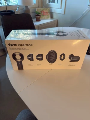 Dyson Supersonic hårfön - Säljer en svart Dyson Supersonic hårfön med flera olika munstycken för styling, inklusive diffuser och koncentrator. Kommer i originalförpackning. Modern design i plast och metall, känd för snabb torkning och skonsam värme för alla hårtyper.