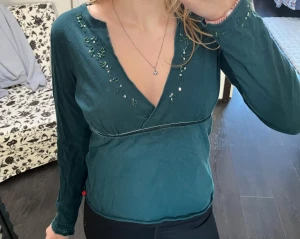 Mörkgrön 2000 top - Säljer denna jättefina topp från esprit och den är i bra skick! Den är i en jättefin mörkgrön färg med fina glitter detaljer och så har den snören så man kan knyta där bak!