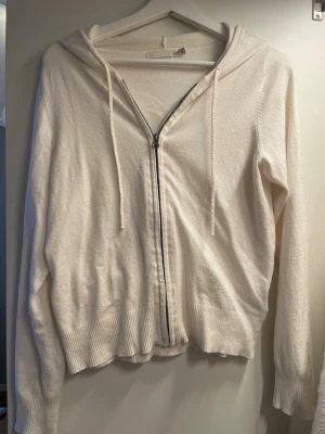 Vit hoodie med dragkedja från lager 157 - Mysig vit hoodie från lager 157 med dragkedja framtill och justerbar huva. Tillverkad i ett mjukt stickat material med ribbade muddar vid ärmslut och nederkant. Perfekt för en chill och avslappnad stil.