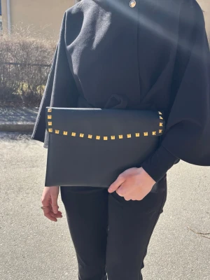 Datorfodral med guldnitar  - Stilrent datorfodral tillverkat av veganskt läder i vattentätt material. Fodralet stängs med knapp. Fodralet skyddar din dator effektivt samtidigt som det ger din outfit en extra touch. ⚜️ Storlek: 34 × 25 cm –  Innifrån 33 x 24 📦  