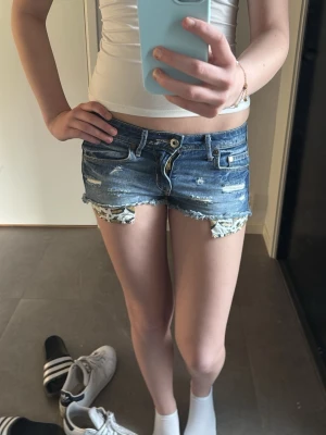 Lågmidjade jeansshorts - Säljer ett par blå jeansshorts. Dem är lågmidjade och är lite slitna i designen. Säljer då dem blivit för små för mig💕
