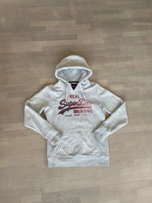 Superdry glitter hoodie grå  - Den är i väldigt bra skick men det ända är två små fläckar kolla bilderna. Den är lite mindre i storleken 