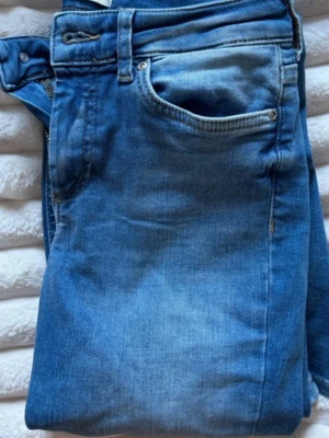 Blå bootcut jeans - Säljer ett par blå bootcut jeans med snygga slitningar och tvättade detaljer. Klassisk femficksmodell och normal midja. Perfekta för dig som gillar en avslappnad men trendig look. Materialet är mjukt denim som sitter skönt hela dagen.