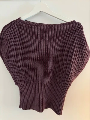 Mörklila chunky stickad tröja - Chunky stickad tröja i mörklila med bred ribbad midja och grovstickat mönster. Tröjan har en avslappnad passform och rund halsringning. Perfekt för lager-på-lager och en cool vardagslook.