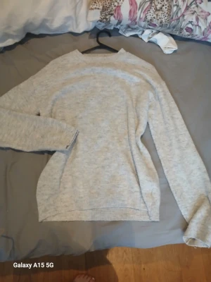 Ljusgrå stickad tröja från H&M - Ljusgrå stickad tröja från H&M med rund halsringning och ribbstickade muddar vid ärmslut och nederkant. Enkel och stilren design som passar perfekt till många olika outfits.