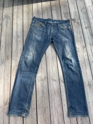 Blå raka jeans från Lee - Snygga blå jeans från Lee med raka ben och klassisk femficksdesign. Jeansen har ljusa slitningar framtill och bak samt Lee-logga på bakfickan. Tillverkade i denim med kontrastsömmar för en tidlös look.