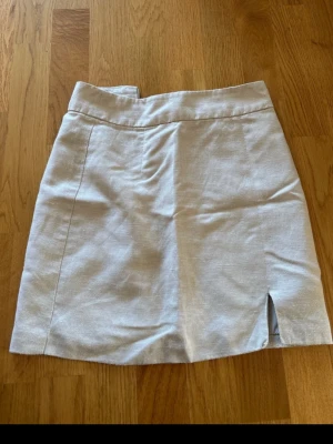 Beige linnekjol - Beige kjol i linnematerial med dragkedja baktill och slits vid ena sidan